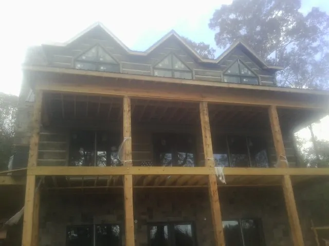 Dormers and porch framing on a large log home under construction — Roof Coating work by our crew in Pleasant Dale
