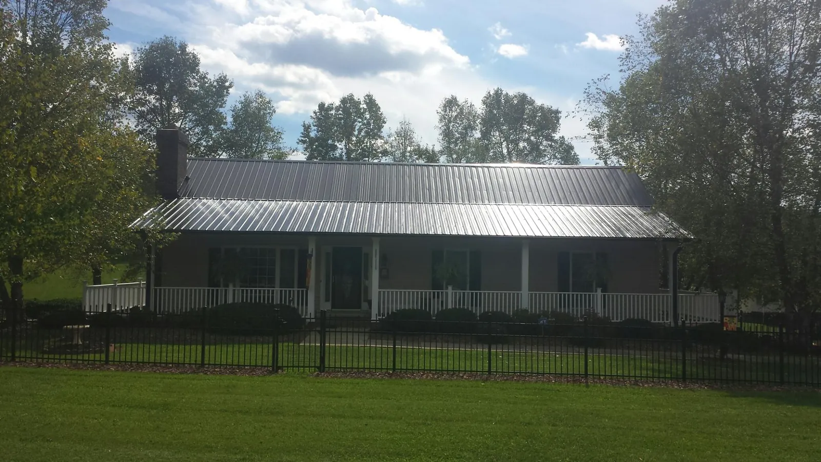 Gray metal roof on a brick ranch with a full width front porch — Gutter Guard Installation work by our crew in Pleasant Dale