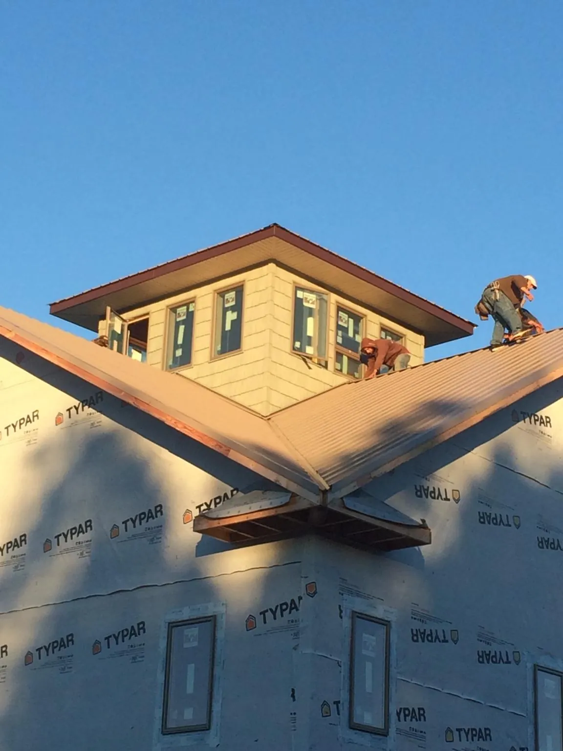 Roofers working around a rooftop cupola on a new metal roof at sunset — Roof Waterproofing in Pleasant Dale by Roofing Brothers